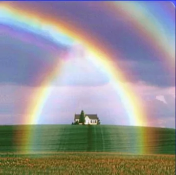 Double rainbow above a small house and green field.