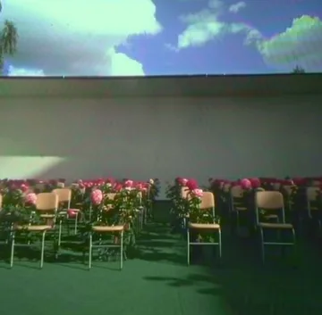 Chairs and flowers beneath a cloud-filled opening.