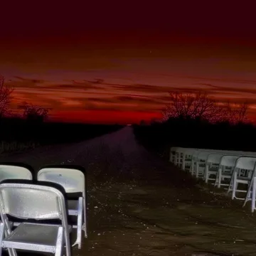 White folding chairs under a red sunset.