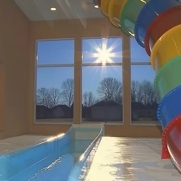 Colorful slide inside a sunlit pool room.