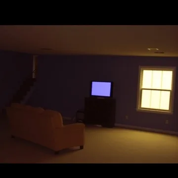 Sofa in a dim room with colored windows.
