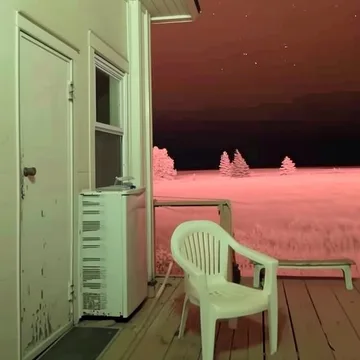 White chair beside a pink kitchen open to dusk.