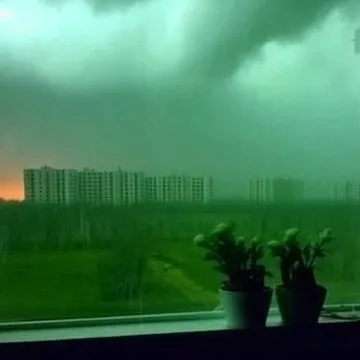 Green storm clouds over distant buildings.