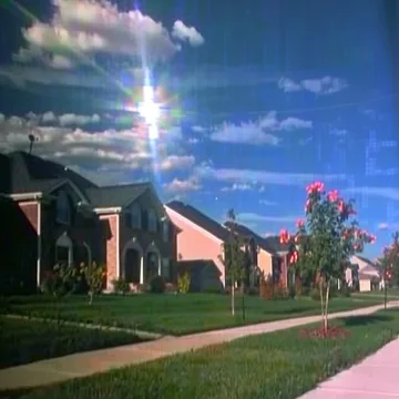 Flowers along a suburban path beneath a rainbow.