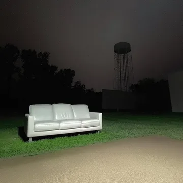White sofa outside beneath a dark water tower.