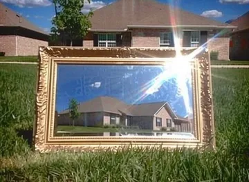 Gold frame standing before a house and lawn.