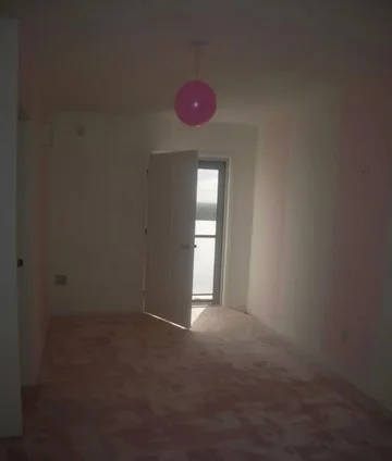 Pink balloon above a bright doorway in an empty room.
