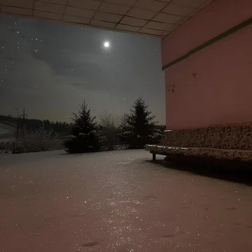 Empty terrace with benches beneath a moonlit sky.