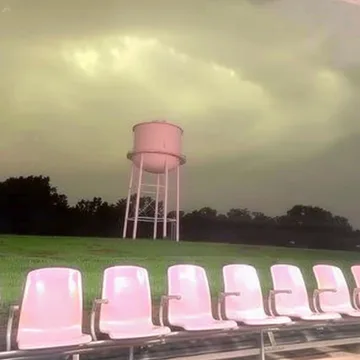 Pink waiting chairs beneath a water tower.