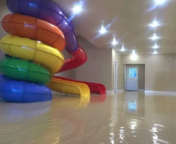 Rainbow slide reflected in a pale flooded room.