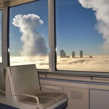 Waiting chair beside windows overlooking towers and clouds.