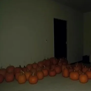 Pumpkins on the floor beside a dark doorway.