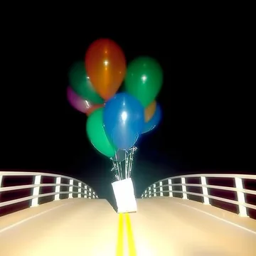 Balloons above an outdoor railing at night.