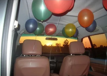Balloons above the seats of a car.