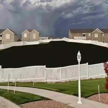 White fence before houses surrounding a dark void.