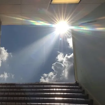 Bright sun above a dark staircase.