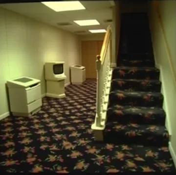 Washing machines beside stairs on patterned carpet.