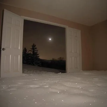 Empty room opening onto a snowy night.