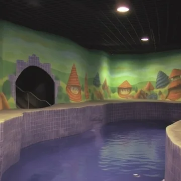 Indoor pool beside a painted landscape mural.