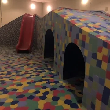Playground tunnels and a slide on patterned flooring.