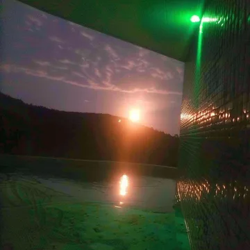 Green lamp above water beneath a sunset opening.