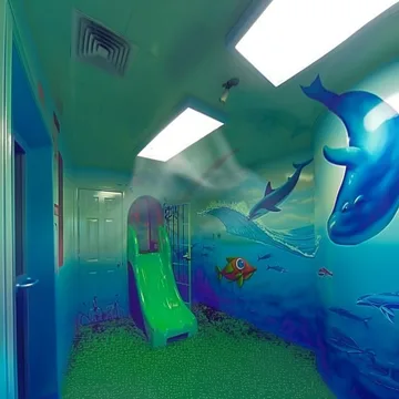 Blue slide beside an underwater mural in a corridor.
