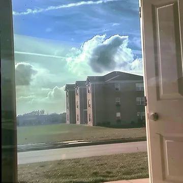 Window overlooking buildings beneath green clouds.