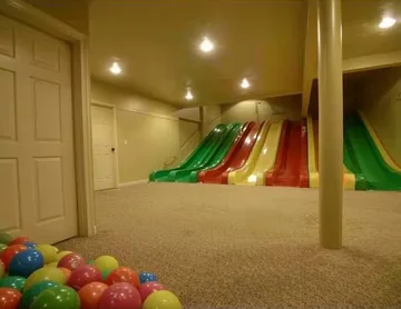 Rainbow slides and balls in a cream-colored room.