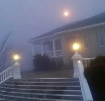Fog around the illuminated steps of a house.