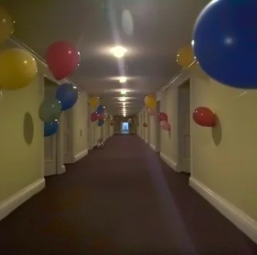 Balloons along a softly lit carpeted hallway.