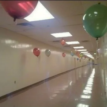 Balloons along a bright reflective corridor.