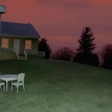 White chairs on a grassy slope at dusk.