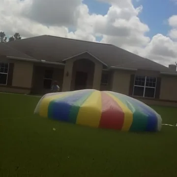 Rainbow inflatable pool on a suburban lawn.