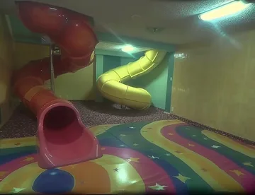 Colorful slide in a green-lit playroom.