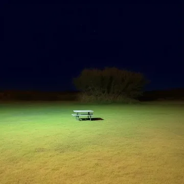 Picnic table in an illuminated field at night.