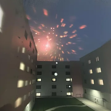 Fireworks above an apartment courtyard at night.