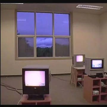 Old computers beneath a window at purple dusk.