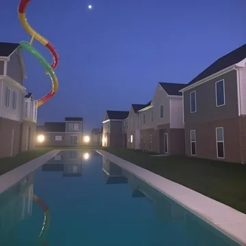 Rainbow slide beside a pool between houses at dusk.