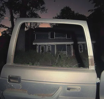 House seen through the rear window of a car at night.