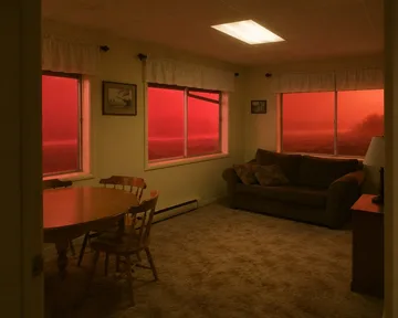 Dark sofa in a kitchen with red-lit windows.