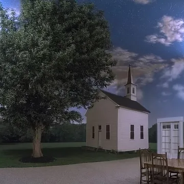 White house and a large tree beneath blue clouds.