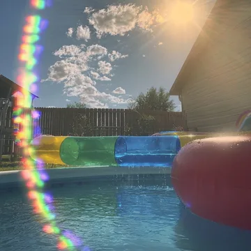 Rainbow reflections in an outdoor inflatable pool.