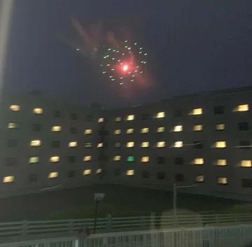 Fireworks above a dark apartment courtyard.