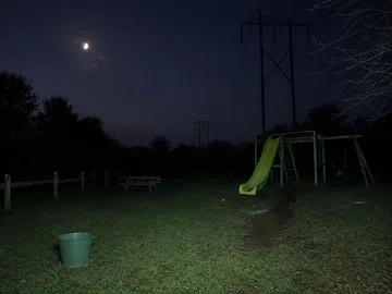 Small green slide on a moonlit lawn.