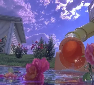 Orange water slide beside flowers under a purple sky.