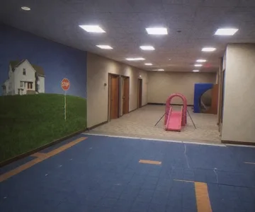 Small pink slide in an empty blue-carpeted corridor.