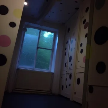 Blue window at the end of a polka-dot hallway.